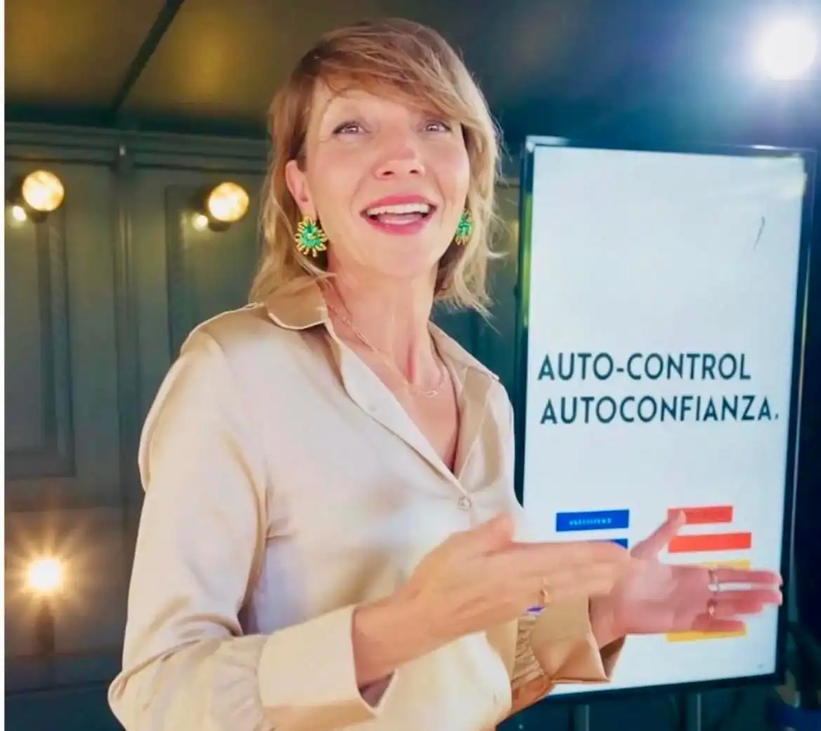 Mujer hablando frente a una pantalla.