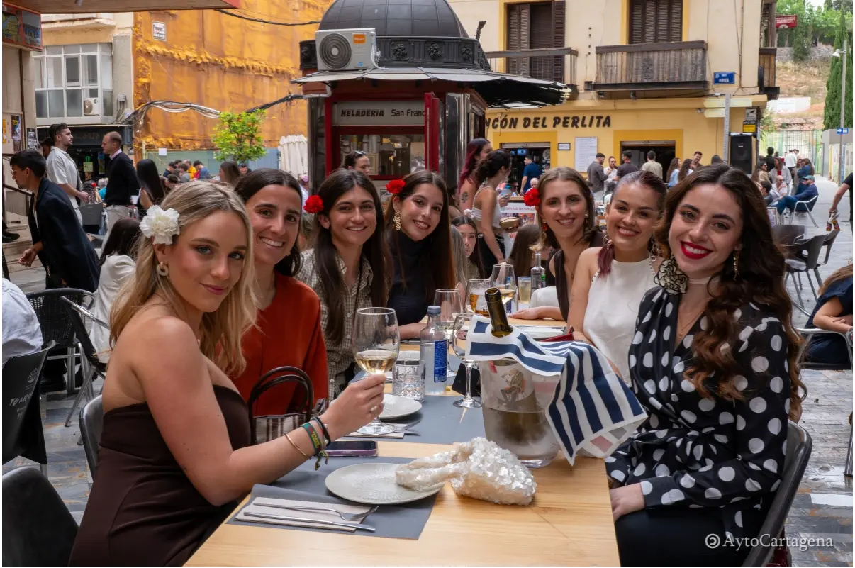 Grupo de amigas disfrutando en una terraza del centro de Cartagena durante las Cruces de Mayo con ambiente festivo y gastronómico