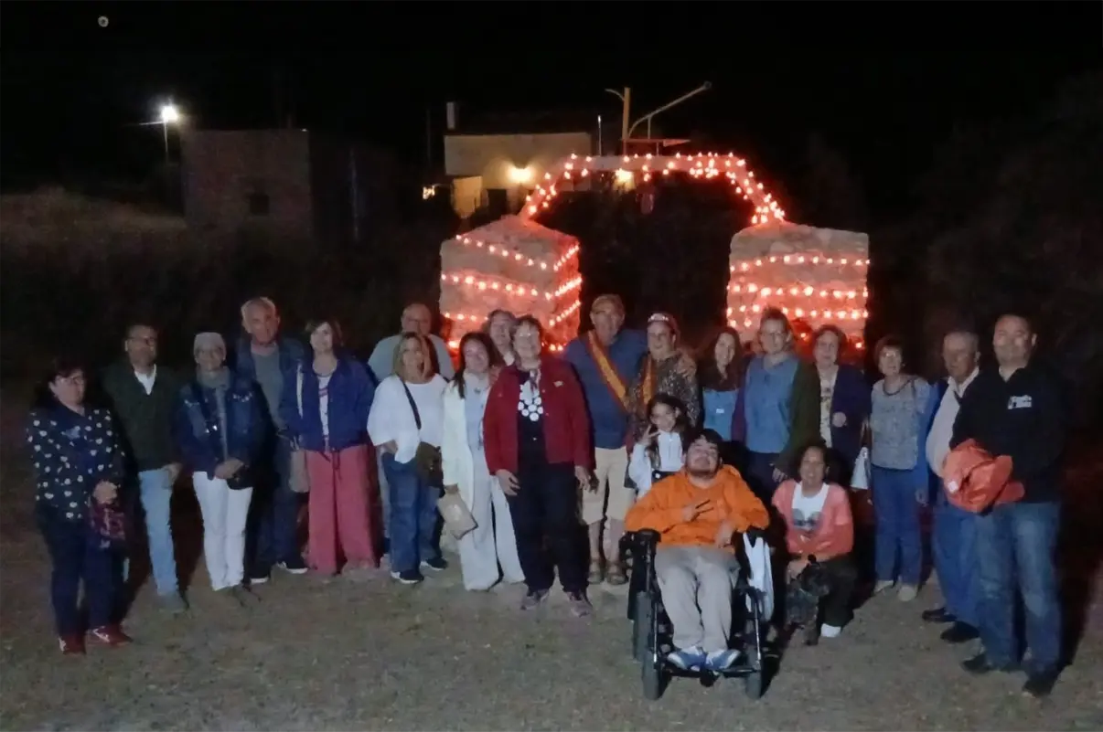 Vecinos de El Campillo de Adentro posan junto al histórico pozo iluminado de naranja por el Día Mundial del Síndrome de Ehlers-Danlos e Hiperlaxitud.